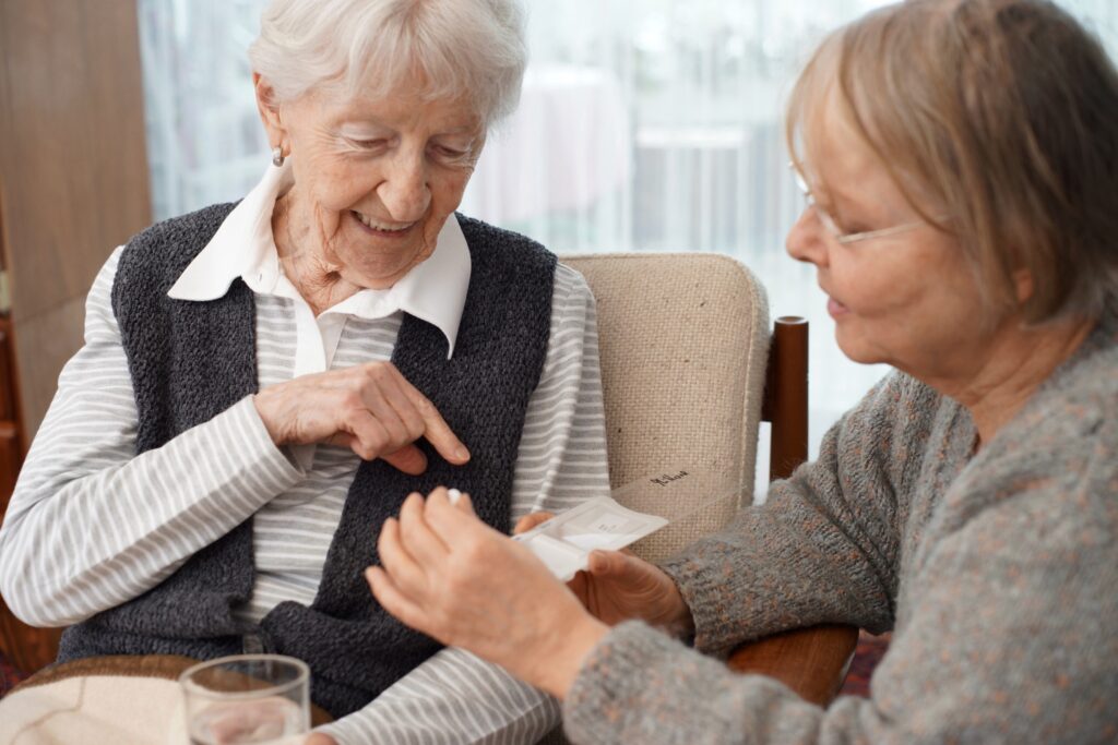 A caregiver helps an senior client take her medications. 